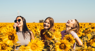 three girls smiling in sunflower fields